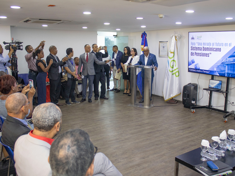 Con la finalidad de debatir y analizar el futuro del sistema de pensiones de la República Dominicana, la Dirección General de Jubilaciones y Pensiones a Cargo del Estado (DGJP) llevó a cabo este martes el foro titulado “Una mirada al futuro en el Sistema Dominicano de Pensiones”, dirigido comunicadores. La ponencia del evento estuvo a cargo del director general de la DGJP, licenciado Juan Rosa, quien destacó la situación actual del sistema dominicano de pensiones, sus principales desafíos, perspectivas de transformación y su impacto social, basándose en tres ejes fundamentales, tales como, ampliar la cobertura del sistema de pensiones, aumentar la suficiencia de las pensiones y revisar el modelo de capitalización individual. El licenciado Rosa puntualizó que “el futuro del sistema de pensiones no puede ser solo una preocupación del Estado, es una responsabilidad compartida que requiere la participación de todos los trabajadores, los empleadores, la sociedad civil y los organismos internacionales”. Con la finalidad de debatir y analizar el futuro del sistema de pensiones de la República Dominicana, la Dirección General de Jubilaciones y Pensiones a Cargo del Estado (DGJP) llevó a cabo este martes el foro titulado “Una mirada al futuro en el Sistema Dominicano de Pensiones”, dirigido comunicadores.
La ponencia del evento estuvo a cargo del director general de la DGJP, licenciado Juan Rosa, quien destacó la situación actual del sistema dominicano de pensiones, sus principales desafíos, perspectivas de transformación y su impacto social, basándose en tres ejes fundamentales, tales como, ampliar la cobertura del sistema de pensiones, aumentar la suficiencia de las pensiones y revisar el modelo de capitalización individual.
El licenciado Rosa puntualizó que “el futuro del sistema de pensiones no puede ser solo una preocupación del Estado, es una responsabilidad compartida que requiere la participación de todos los trabajadores, los empleadores, la sociedad civil y los organismos internacionales”.